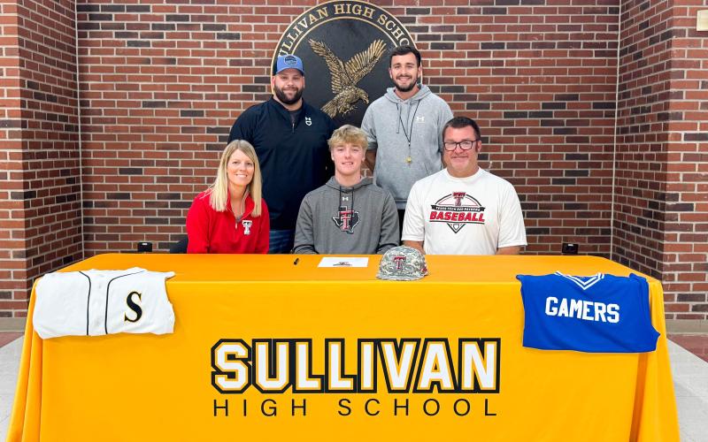 FIGHT, RAIDERS, FIGHT! Sullivan pitcher Drake Gawer (center) has signed with Texas Tech University. He is pictured seated alongside his mother, Tara (left), and his father, Matt (right). Standing in the back row are his high school head coach, Ian Whitson (left), and assistant coach, Jordan Mehl (right). Submitted photo Article Image Alt Text