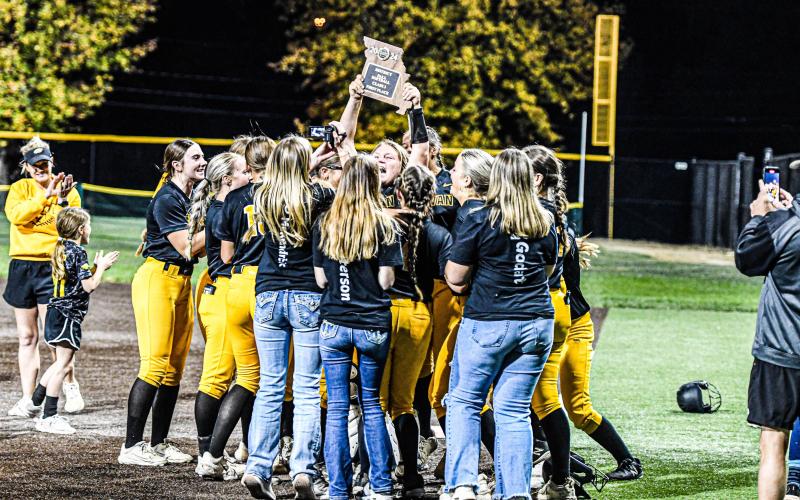 HANG IT IN THE RAFTERS. Dorie Richardson holds the district plaque after the championship. Photo by Extra Innings Photography Article Image Alt Text