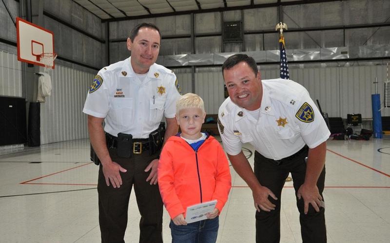 Kindergarten student Levi Vogt presenting the Kindergarten thank you card to members of the Franklin County Sheriff's Department.