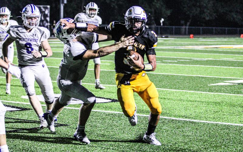 STIFF-ARM. Robert York II (3) sneaks away from the pocket and stiff-arms a Lion. Photo by Wyatt Hardy Article Image Alt Text