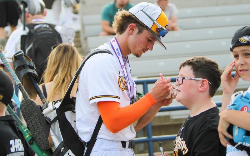 LANDEN DOZA (left) signs a baseball for a fan. Photo by Wyatt Hardy Article Image Alt Text