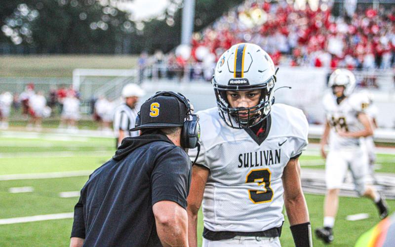 COMMANDERS-IN-CHIEF. Head coach Eddie Haar gives the play call to quarterback Robert York II (3) in their battle against St. Clair on Sep. 15. Photo by Wyatt Hardy Article Image Alt Text