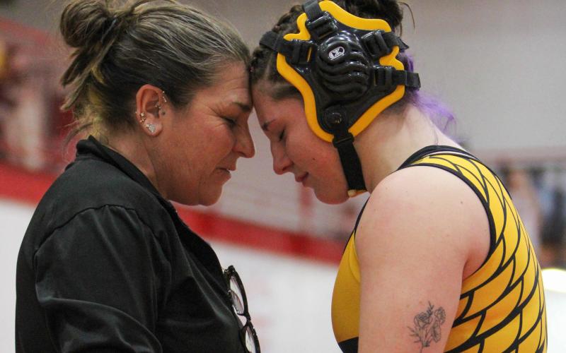 RISE ABOVE. Chloe Carson (right) received comfort from assistant coach Heidi Blankenship (left) before she took the mat for the district championship. Photo by Wyatt Hardy Article Image Alt Text