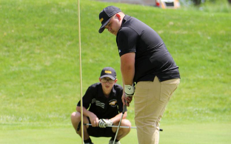 ON PAR. Robert Garrett (right) is pictured putting, while Logan Podner (left) sits and watches him. Photo by Wyatt Hardy Article Image Alt Text