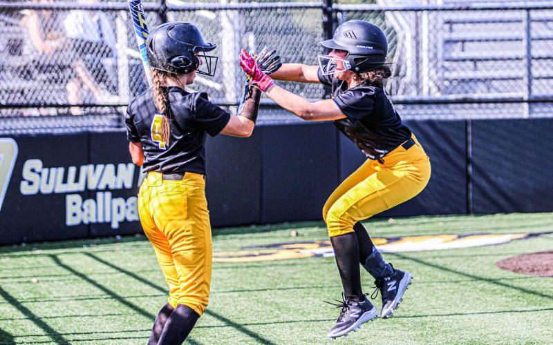 PUNCH IT HOME. Freshman Kennedi Roach (right) stole home against the Zizzers for her first-ever score and returned to the dugout to high-five Ava Declue (left). Photo by Wyatt Hardy Article Image Alt Text